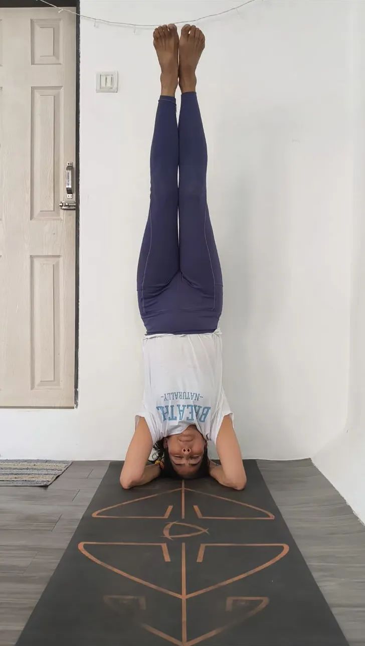 Headstand against a wall on a patterned mat